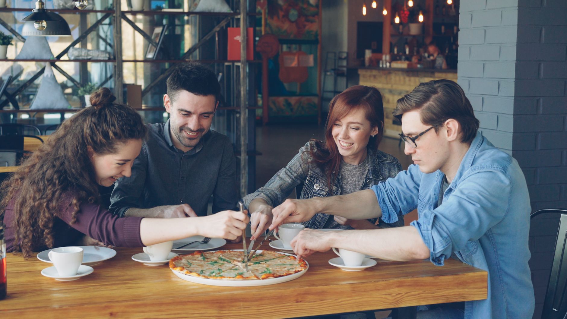 A full table of friends sharing a meal at a busy restaurant