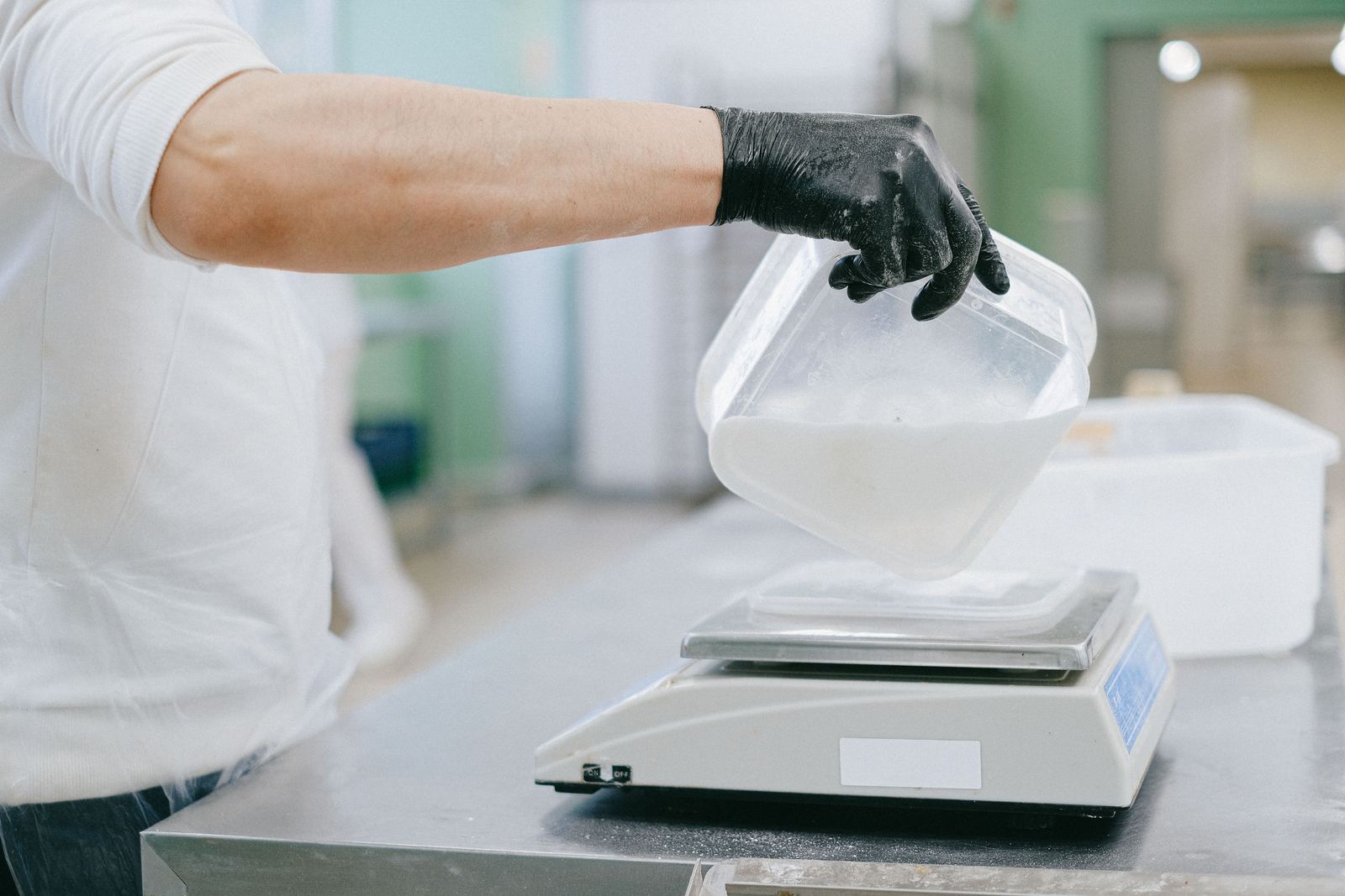 Chef in a kitchen carefully measuring ingredients using a digital scale